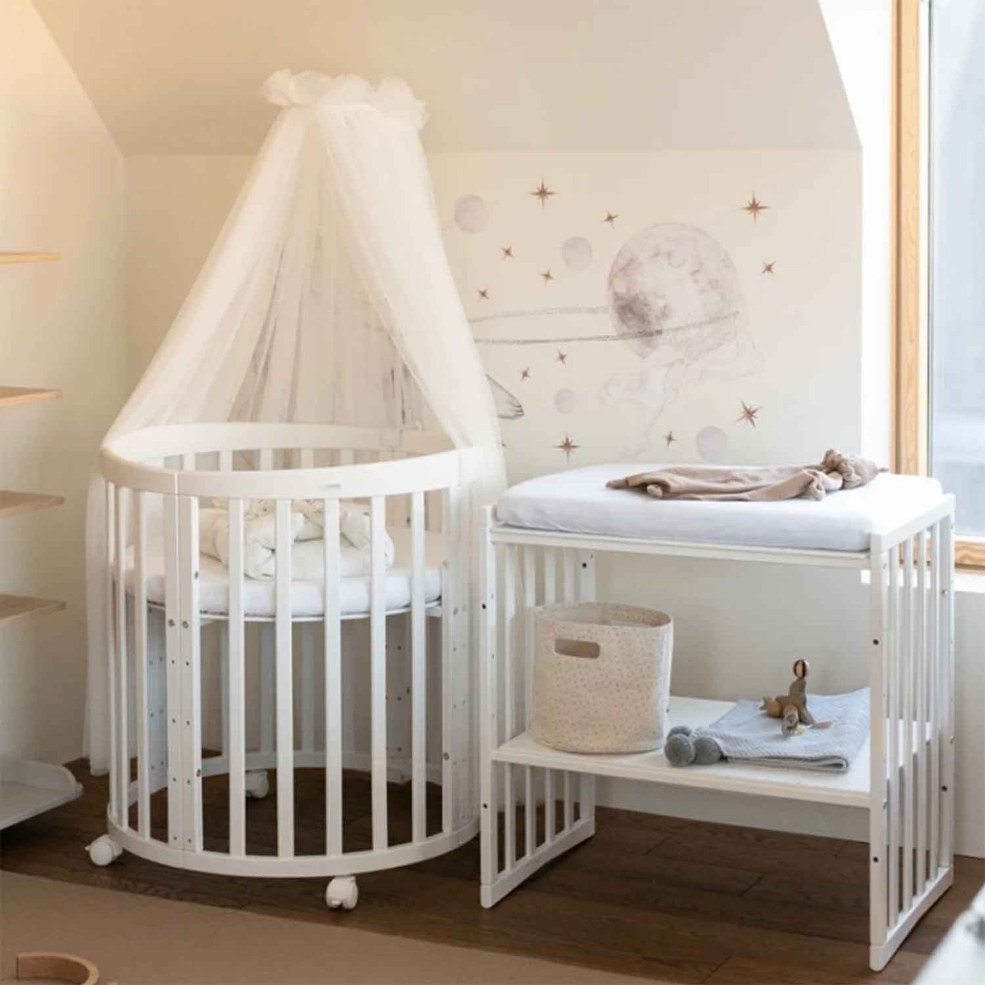 Biela rastúca detská postieľka s baldachýnom v detskej izbe, okrúhla postieľka na kolieskach s prebaľovacím pultom v jemnom škandinávskom štýle