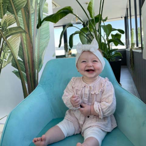 Usmiate bábätko v jemnom detskom oblečení s čelenkou, inšpirácia pre štýlové a pohodlné outfity BySues pre najmenších.