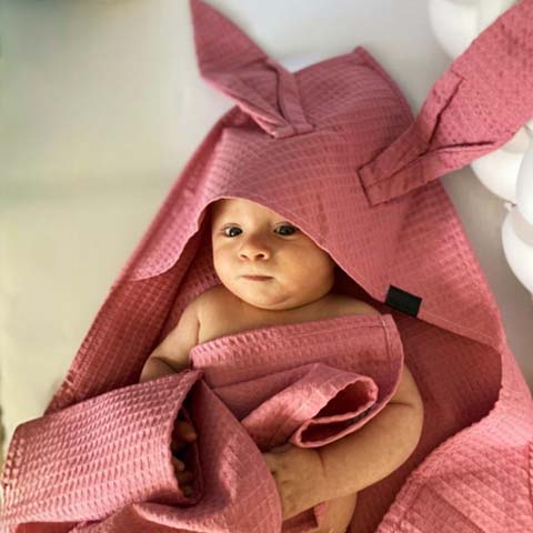Bábätko zabalené v mušelínovej osuške BySues s kapucňou, jemná a savá osuš­ka vhodná na kúpanie novorodencov a bábätiek.